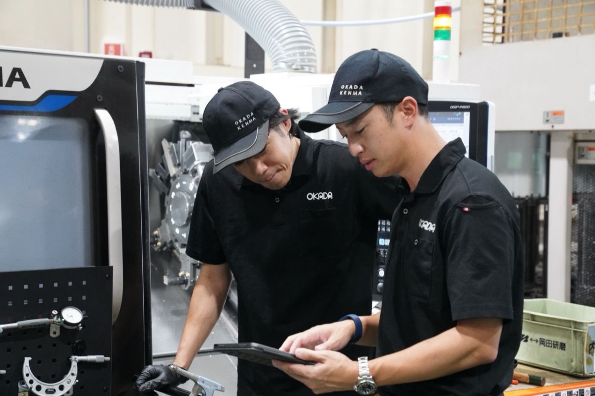 タブレットをのぞき込みながら情報を共有する岡田研磨の2人の社員